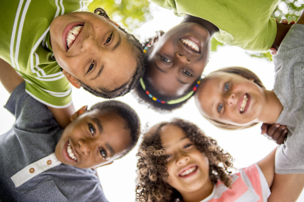 Children with heads together looking down at camera